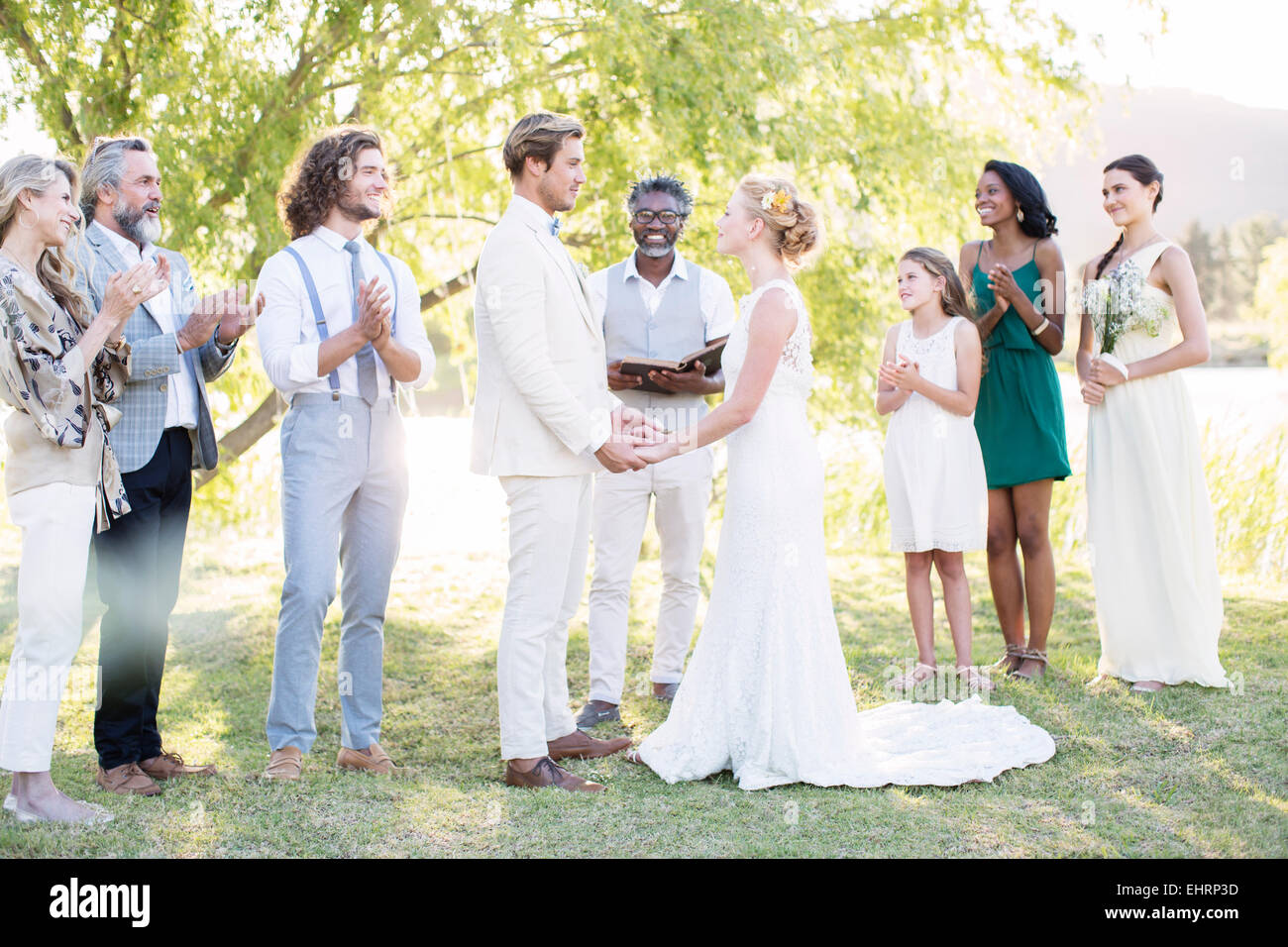 Young couple and guests during wedding ceremony in domestic garden Stock Photo