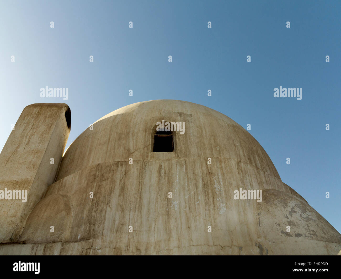Small house with single dome and small window with adjoining chimney against a blue sky Egypt Africa Stock Photo