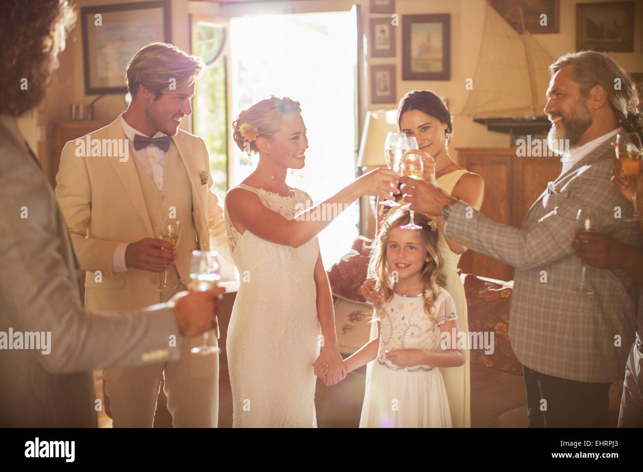 Young couple and guests toasting with champagne during wedding reception in domestic room Stock Photo
