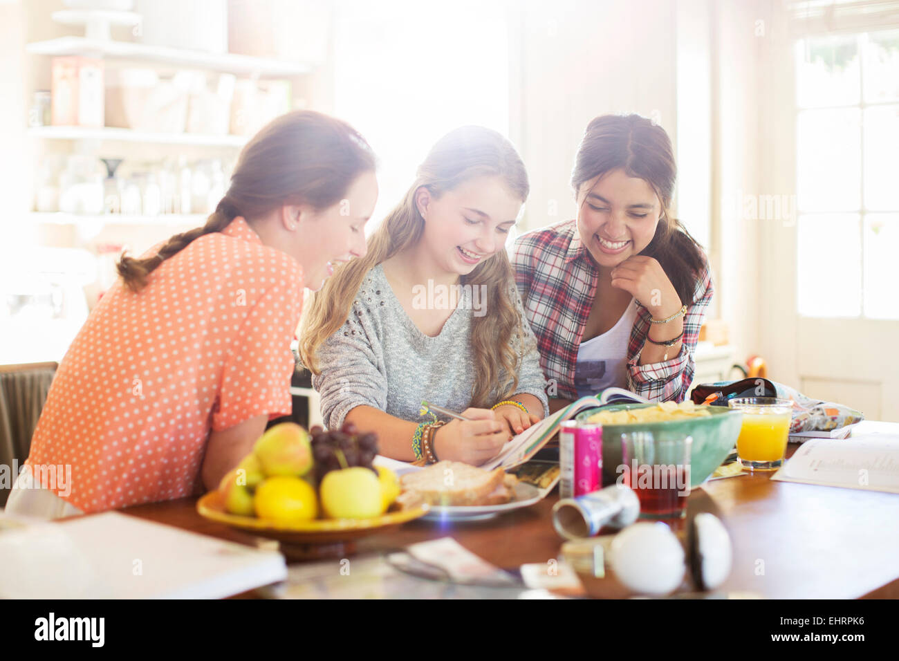 Three teenage girls learning at table in dining room Stock Photo