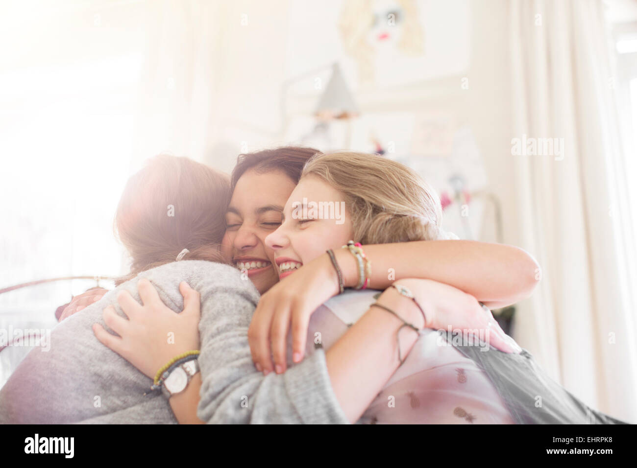 Three teenage girls embracing at home Stock Photo
