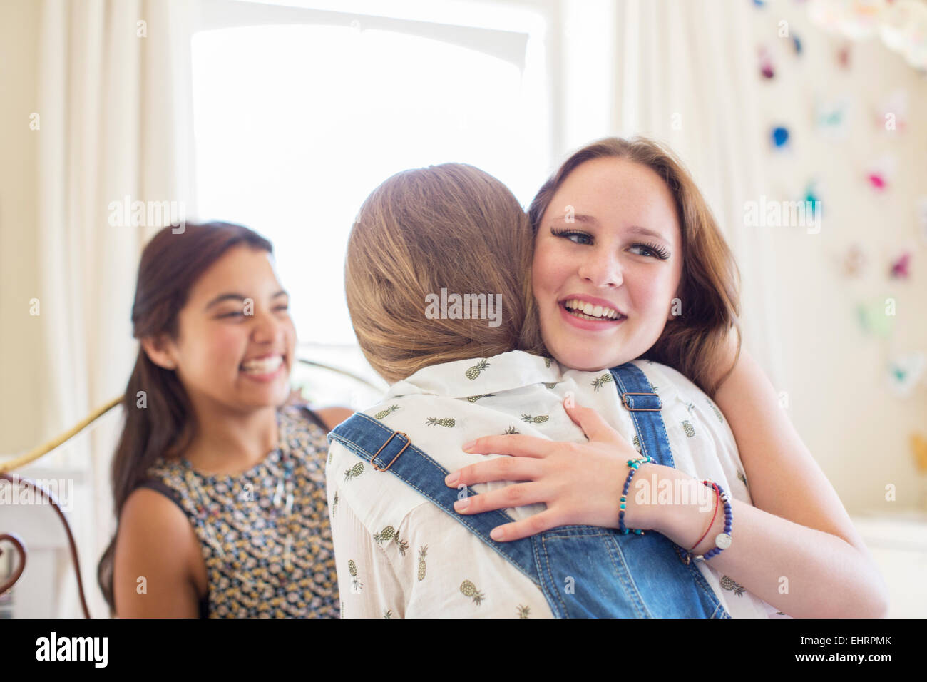 Three teenage girls embracing in bedroom Stock Photo
