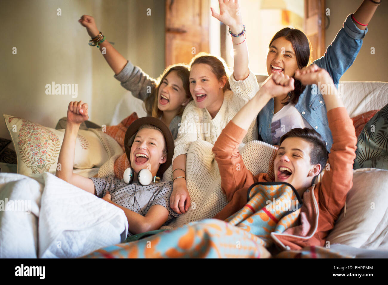 Group Of Teenagers Having Fun While Watching Tv On Sofa Stock Photo
