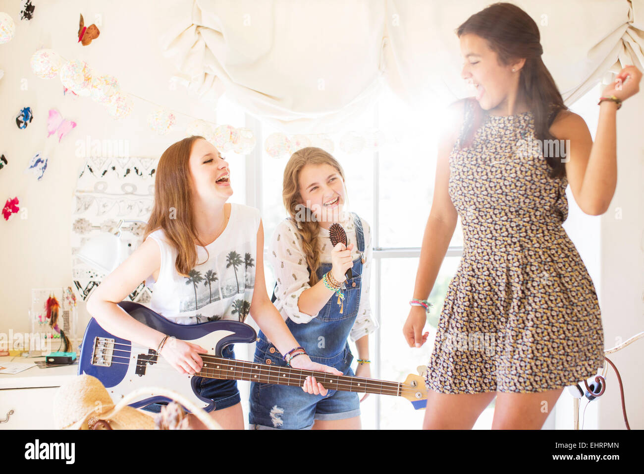 Three teenage girls playing music and singing in room Stock Photo