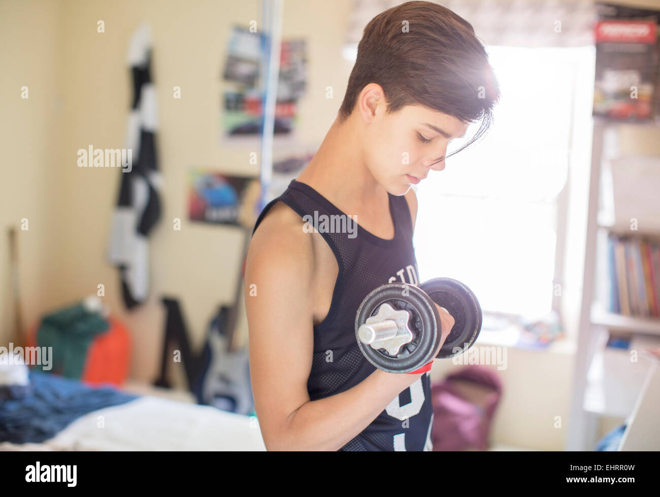 Teenage boy exercising with dumb bell Stock Photo