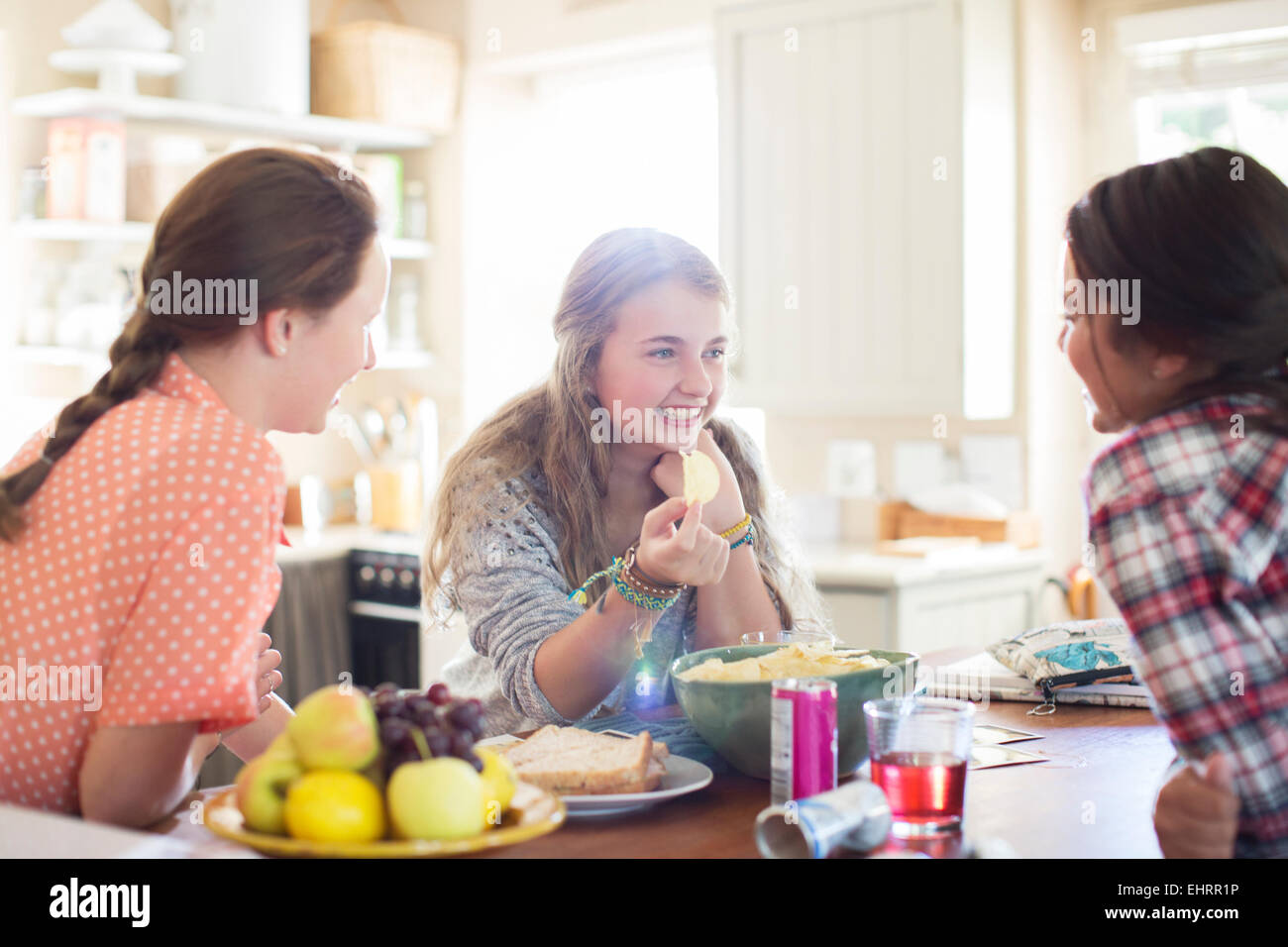 Three teenage girls talking at table in dining room Stock Photo