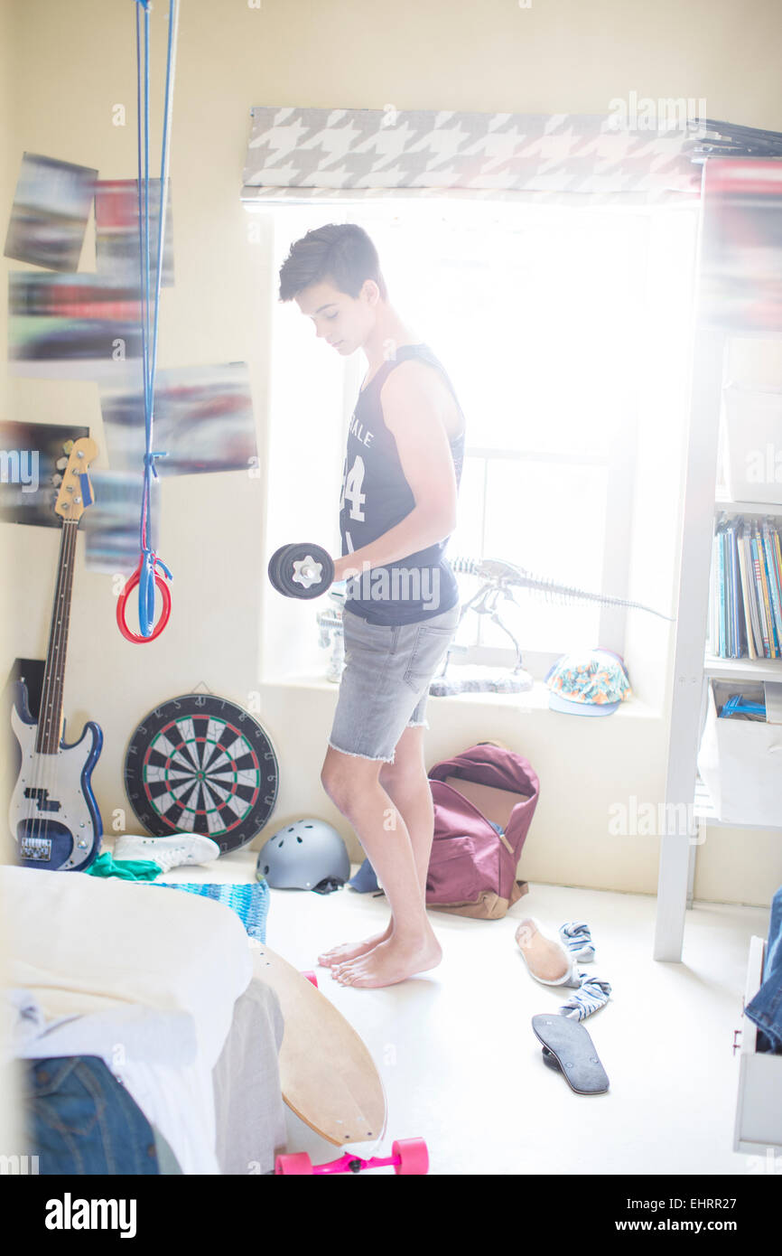 Teenage boy exercising with dumb bell in his room Stock Photo