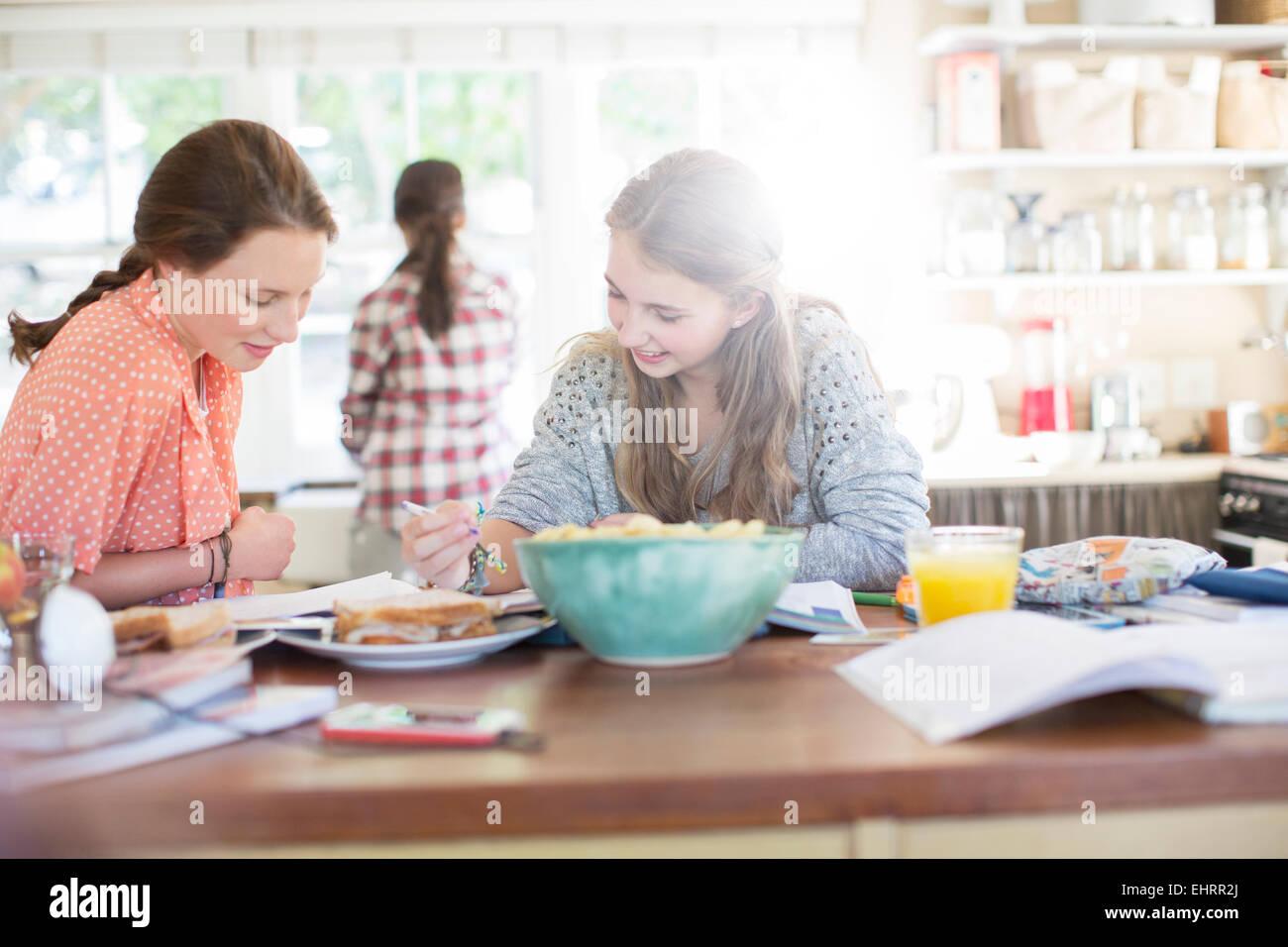Teenage girls learning at table in kitchen Stock Photo