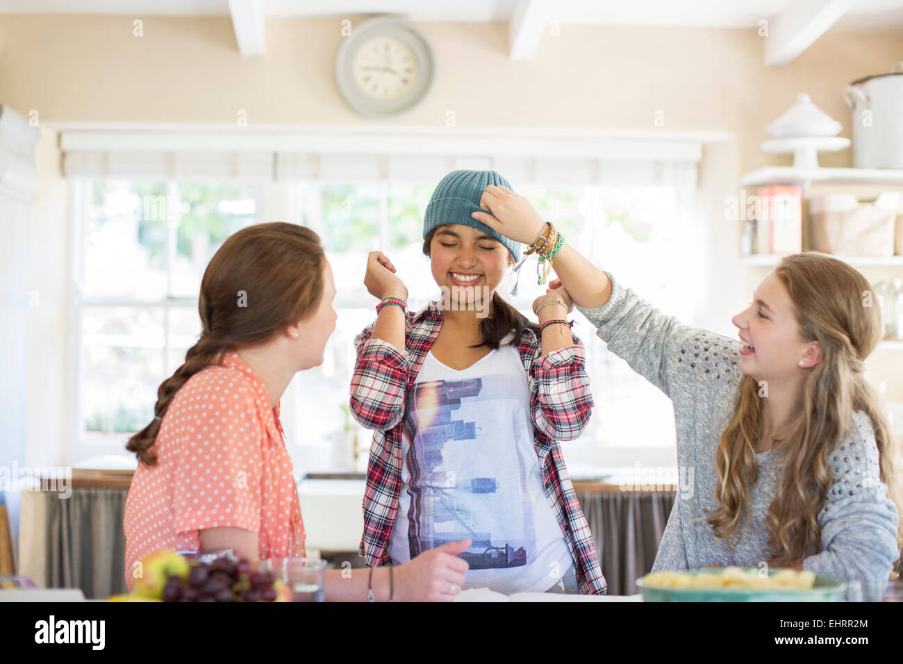 Three teenage girls playing with beanie in dining room Stock Photo