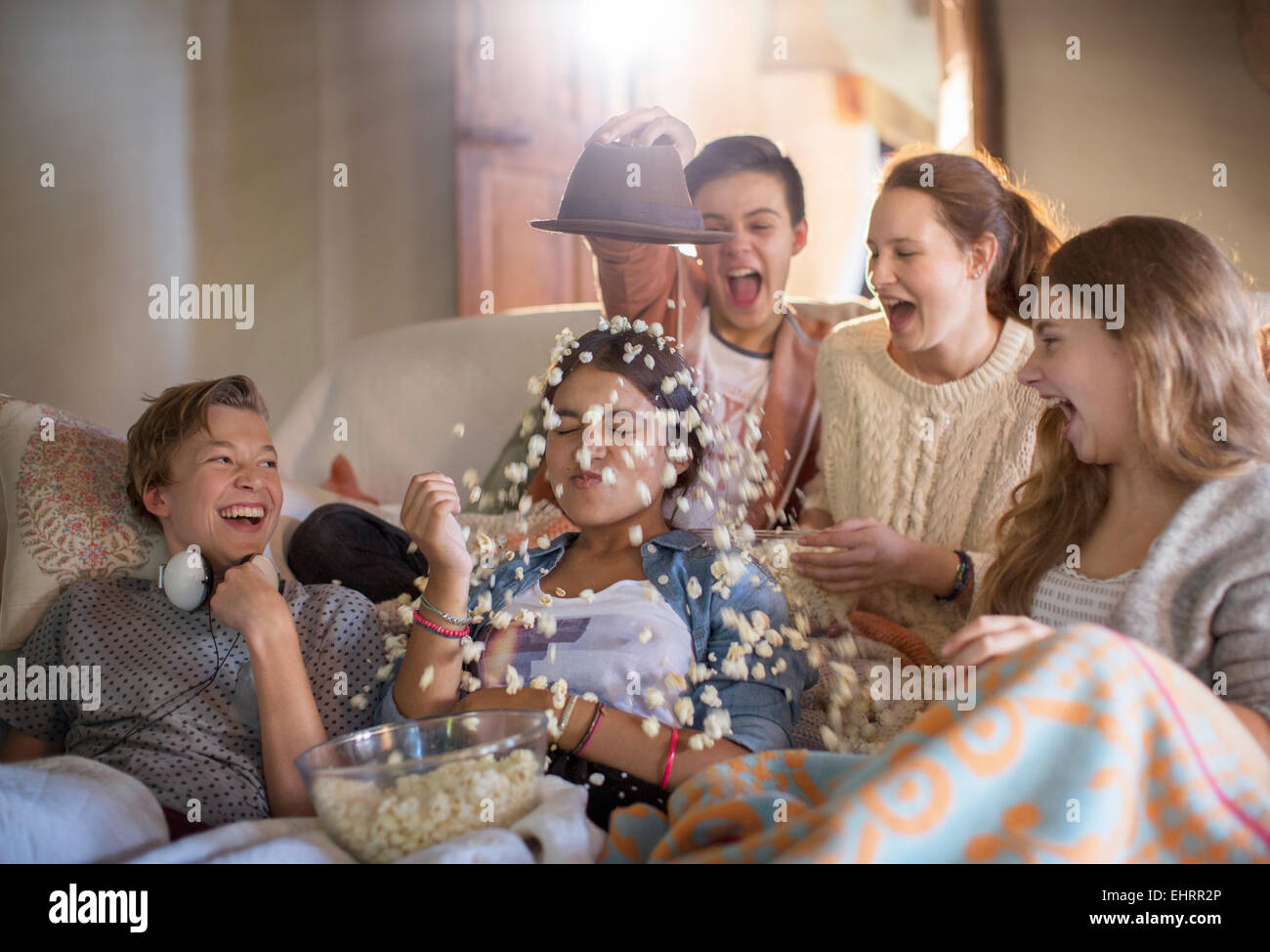 Group of teenagers throwing popcorn on themselves while sitting on sofa Stock Photo