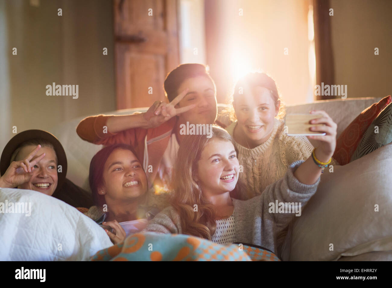 Group of smiling teenagers taking selfie on sofa in living room Stock Photo