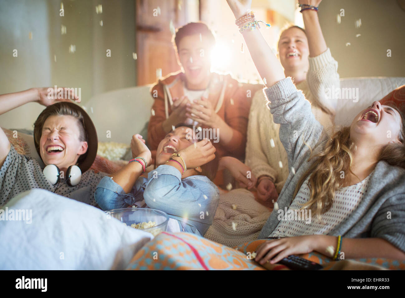 Group of teenagers throwing popcorn on themselves on sofa Stock Photo