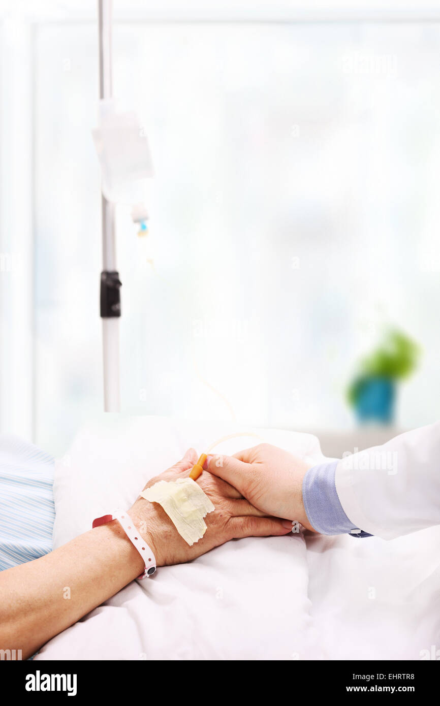 Doctor giving assurance to a patient with an IV drip attached to his hand in a hospital Stock Photo