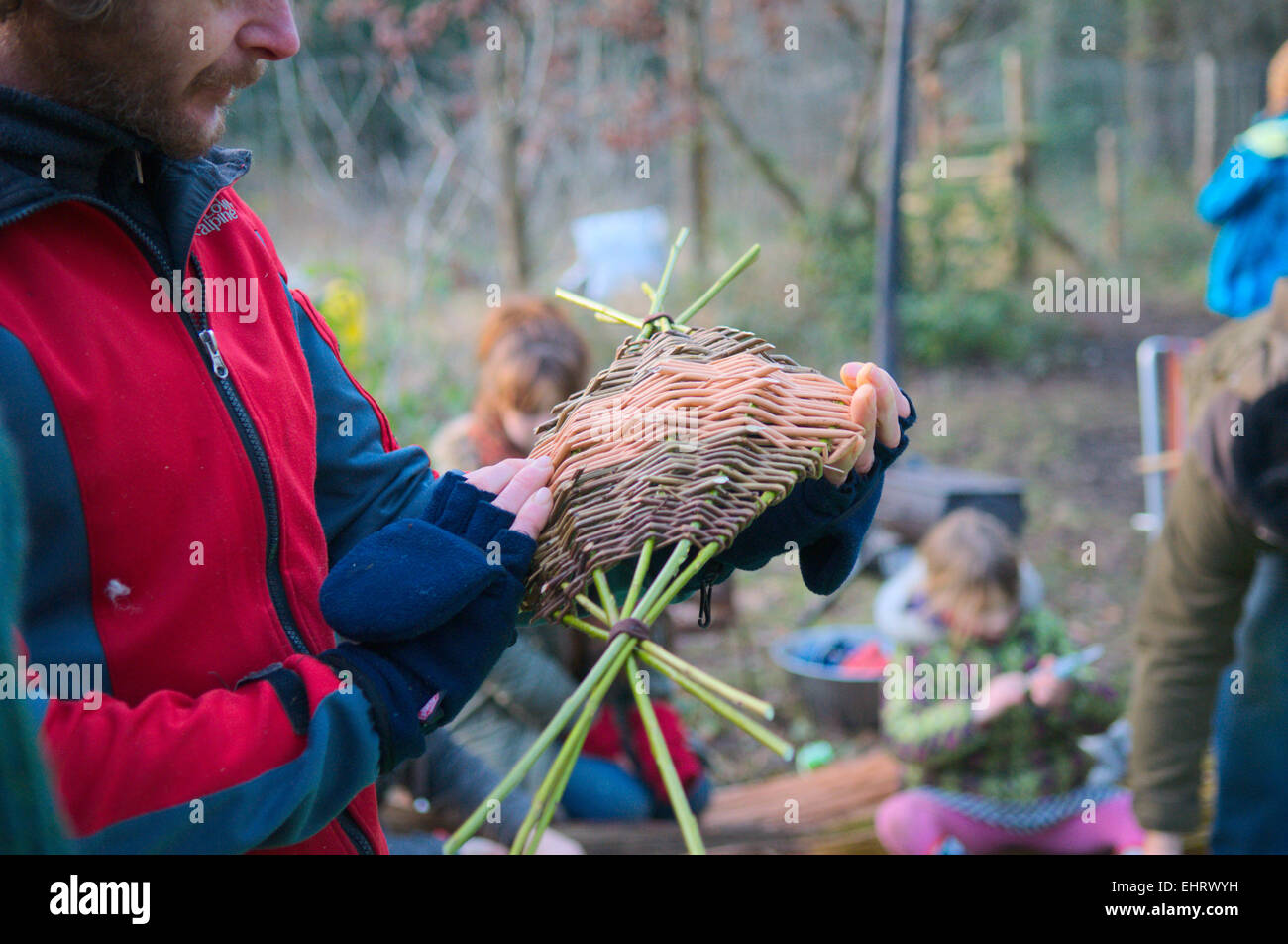 Man examining a willow basket he has been weaving at outdoor coppicing and craft festival, Bristol, UK Stock Photo