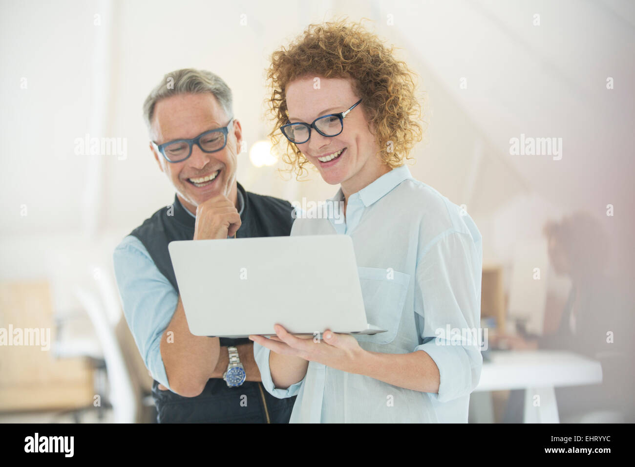 Two smiling office workers using laptop Stock Photo