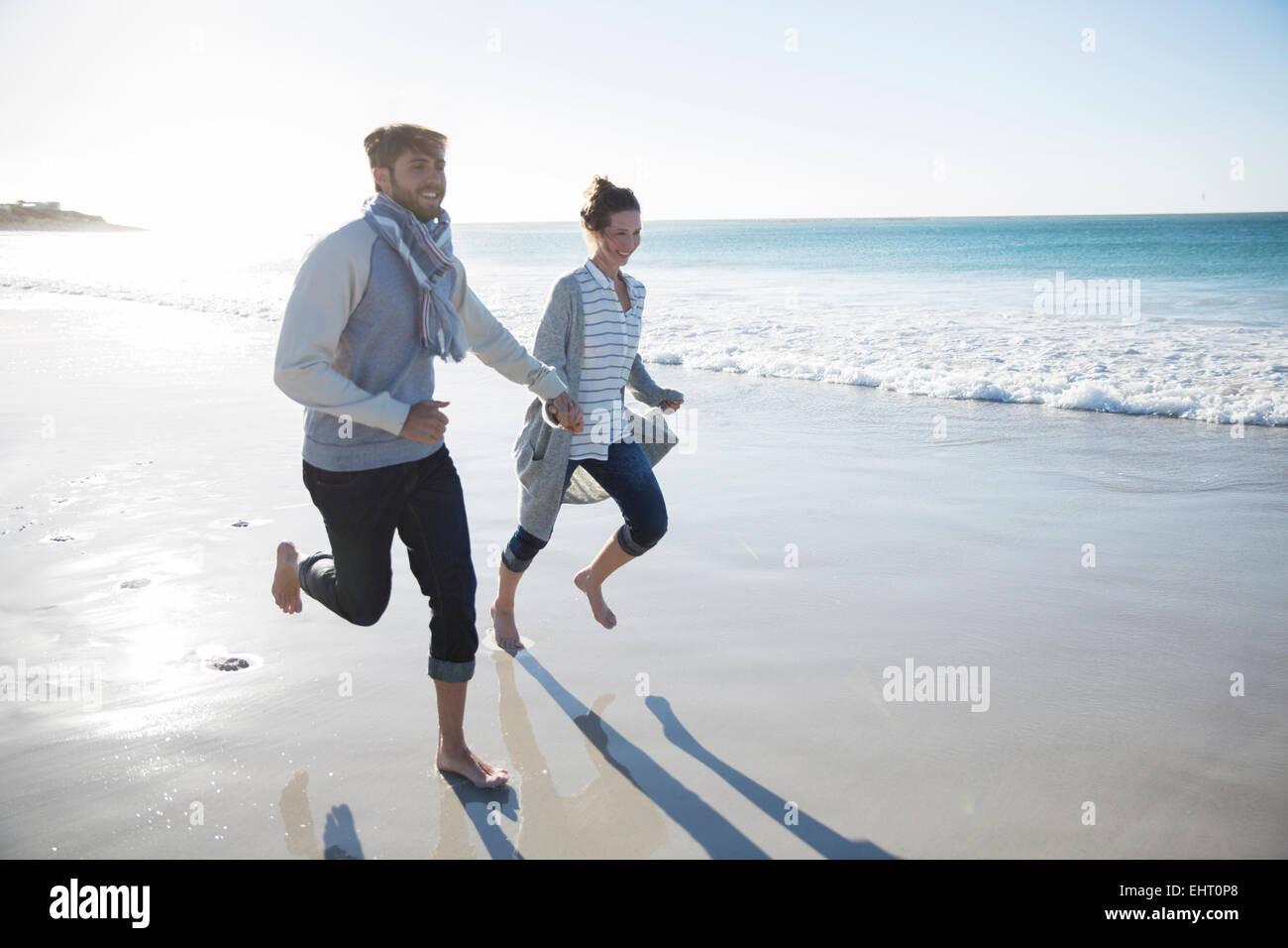 Young couple holding hands and running on beach Stock Photo - Alamy