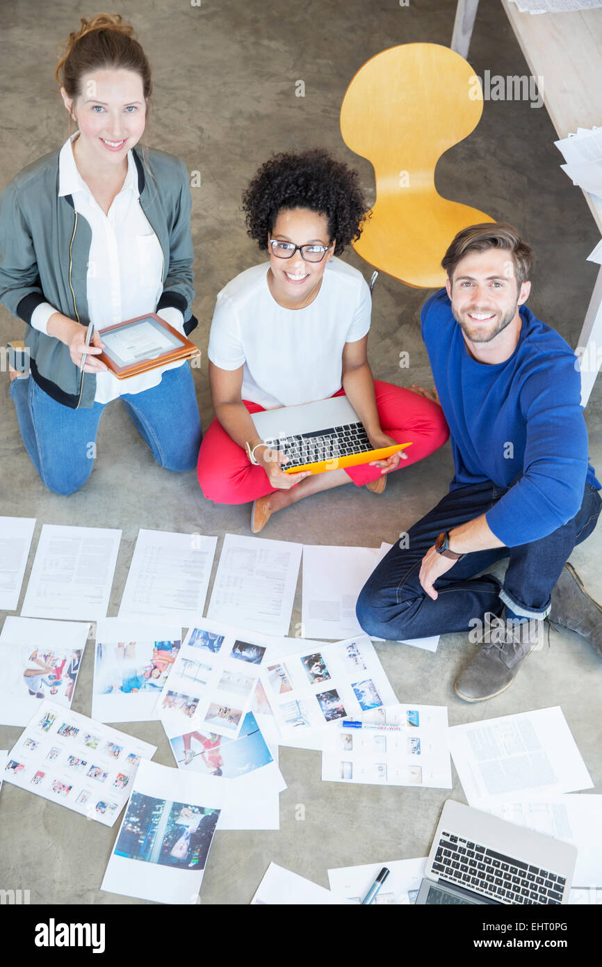 Portrait of three young people sitting on floor and working together Stock Photo