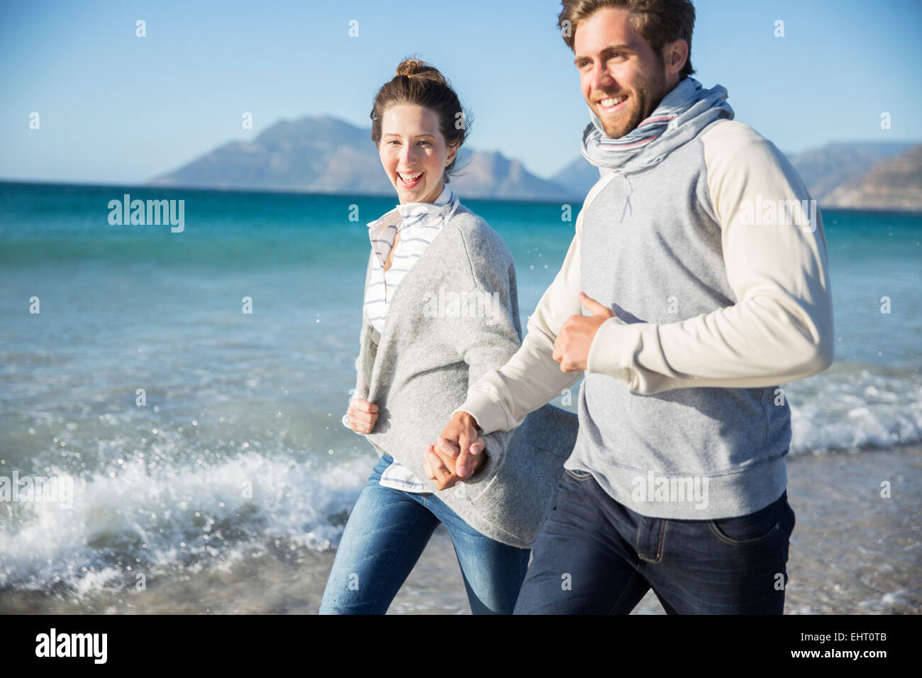Young couple holding hands and walking on beach Stock Photo