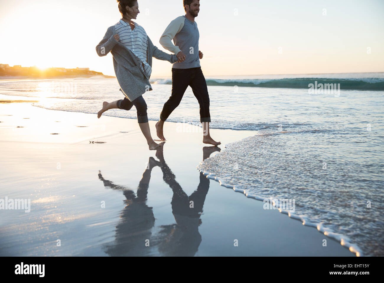 Young couple holding hands and running on beach Stock Photo - Alamy