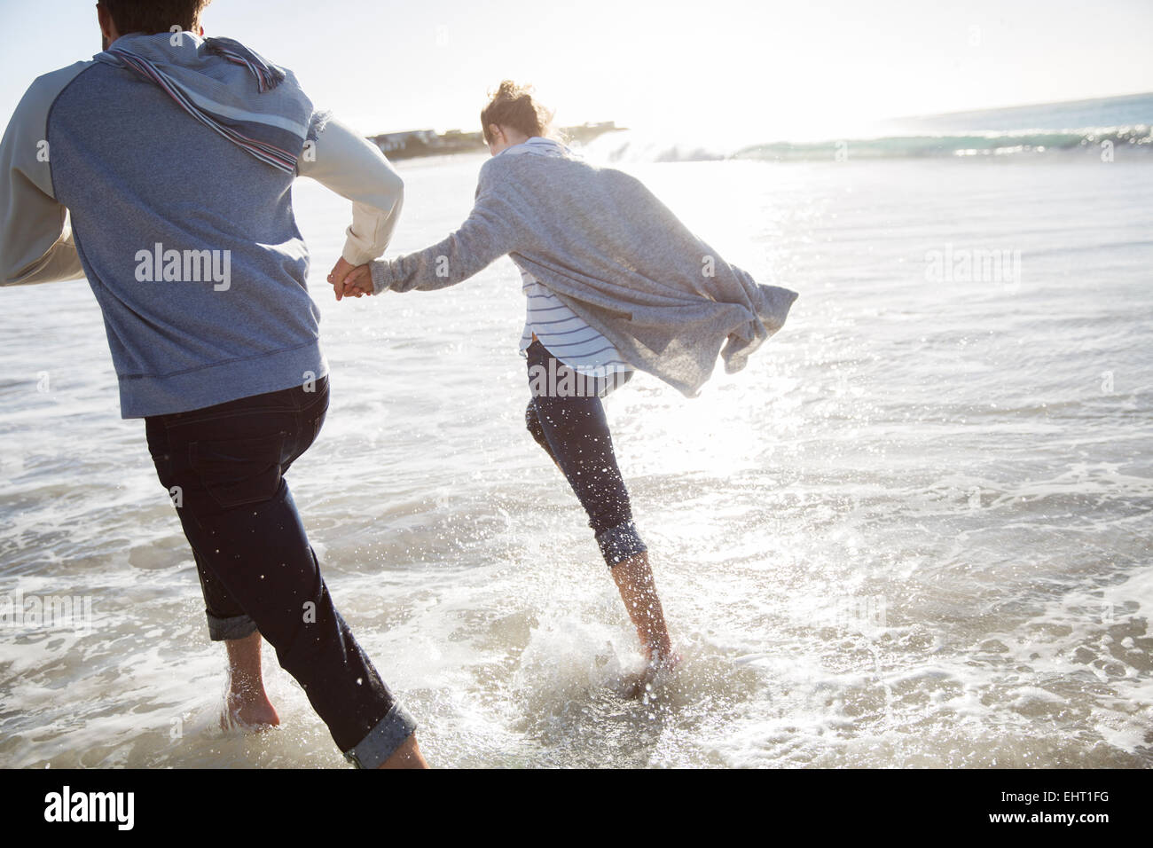 Young couple holding hands and running on beach Stock Photo - Alamy