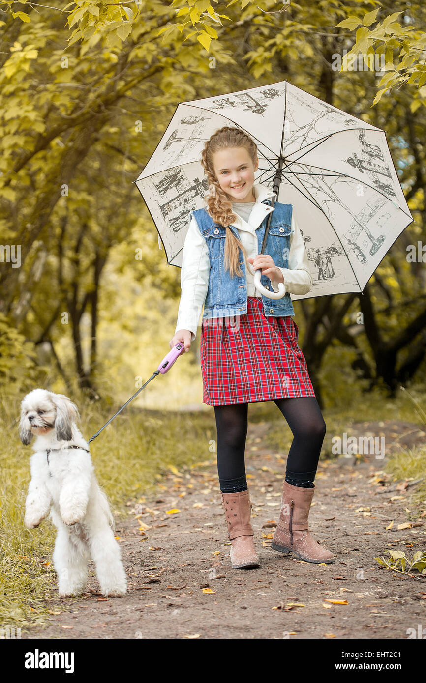 Smiling fashionista posing with dog in park Stock Photo