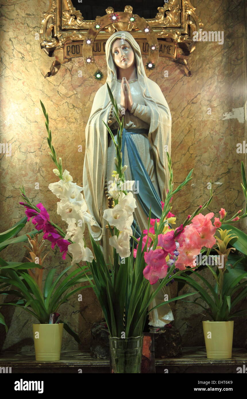 Virgin mary statue with flowers in niche Stock Photo - Alamy