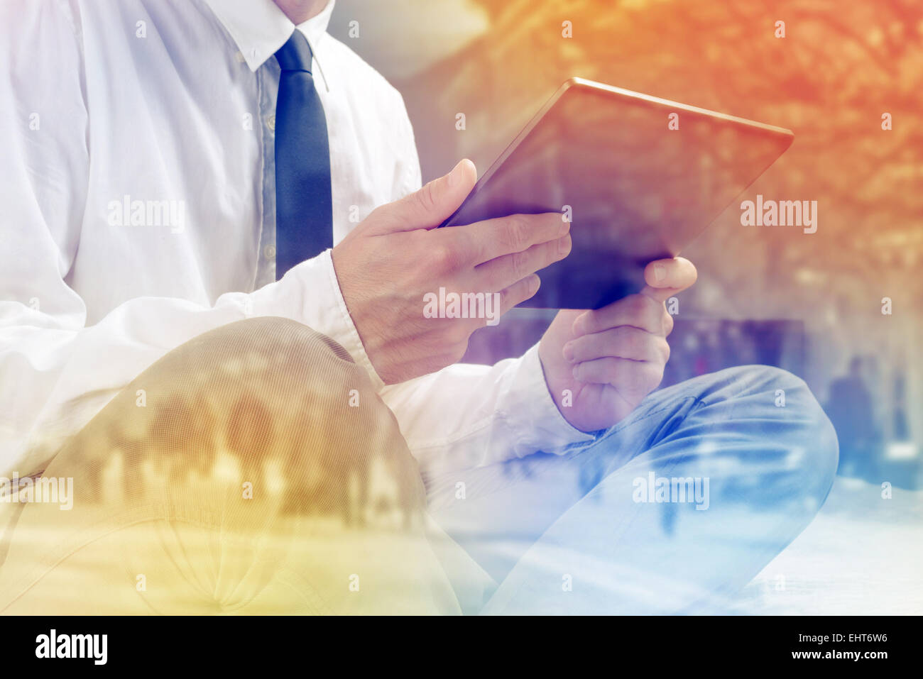 Lonely Businessman with Digital Tablet Computer in Hotel Room, Browsing Internet while sitting on a bed. Stock Photo