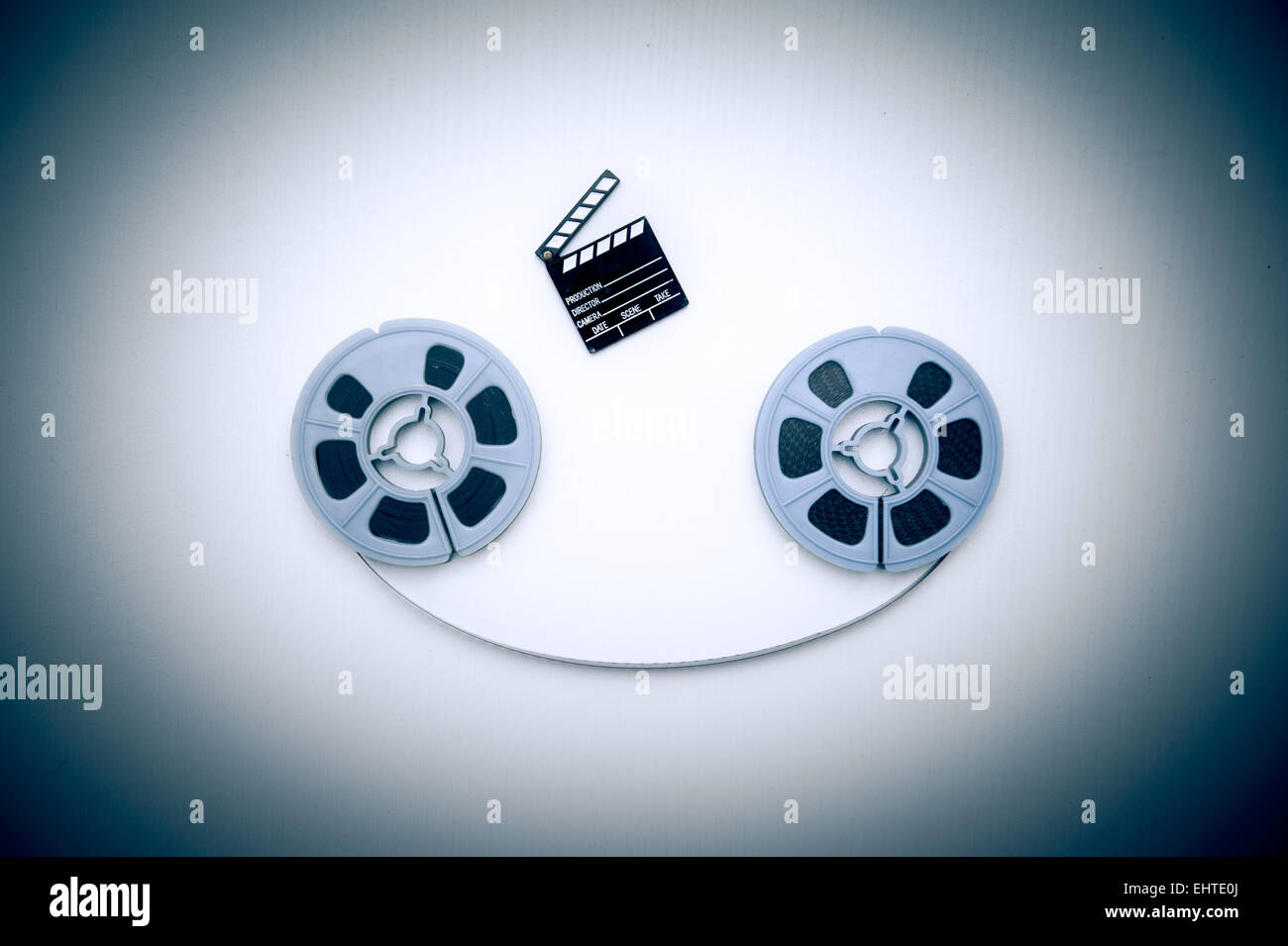 Two 8mm blue reels horizontally connected with film and a little clapper board vintage color effect Stock Photo