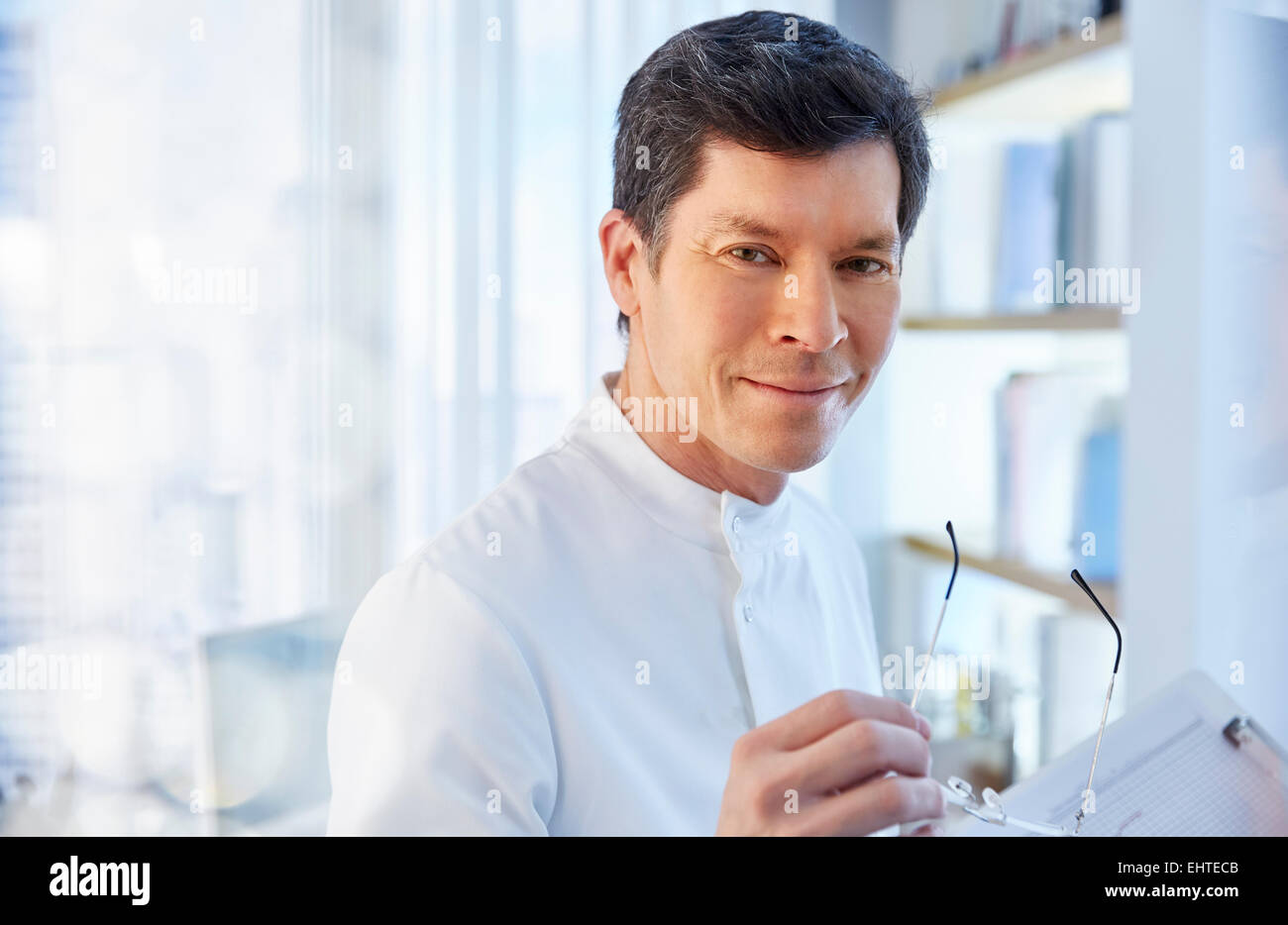 View of man in laboratory holding glasses looking at camera Stock Photo