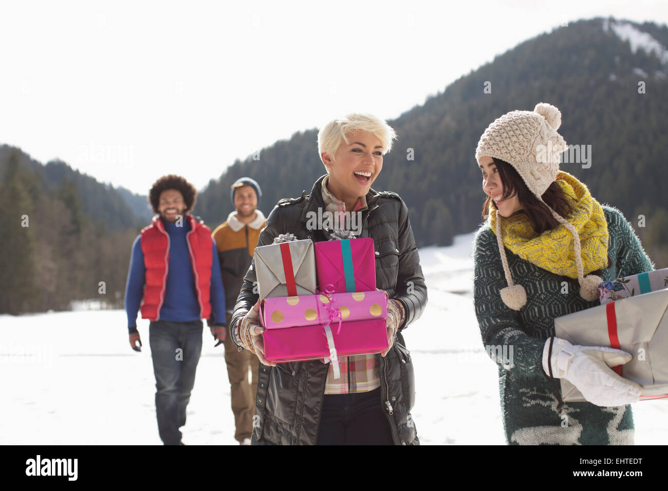Friends carrying Christmas gifts in snow Stock Photo