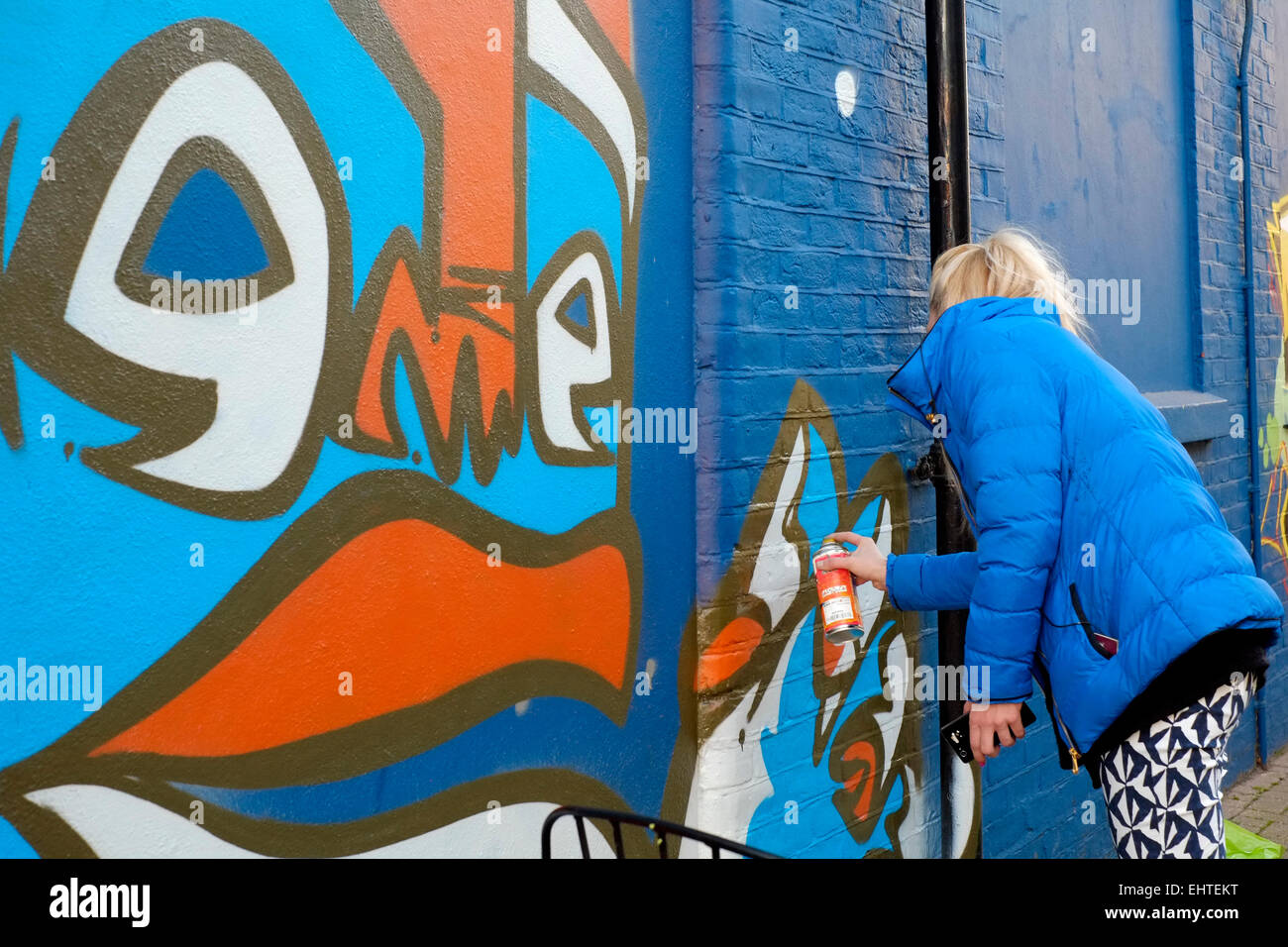 young female street artist spray paints her art onto a wall Stock Photo ...