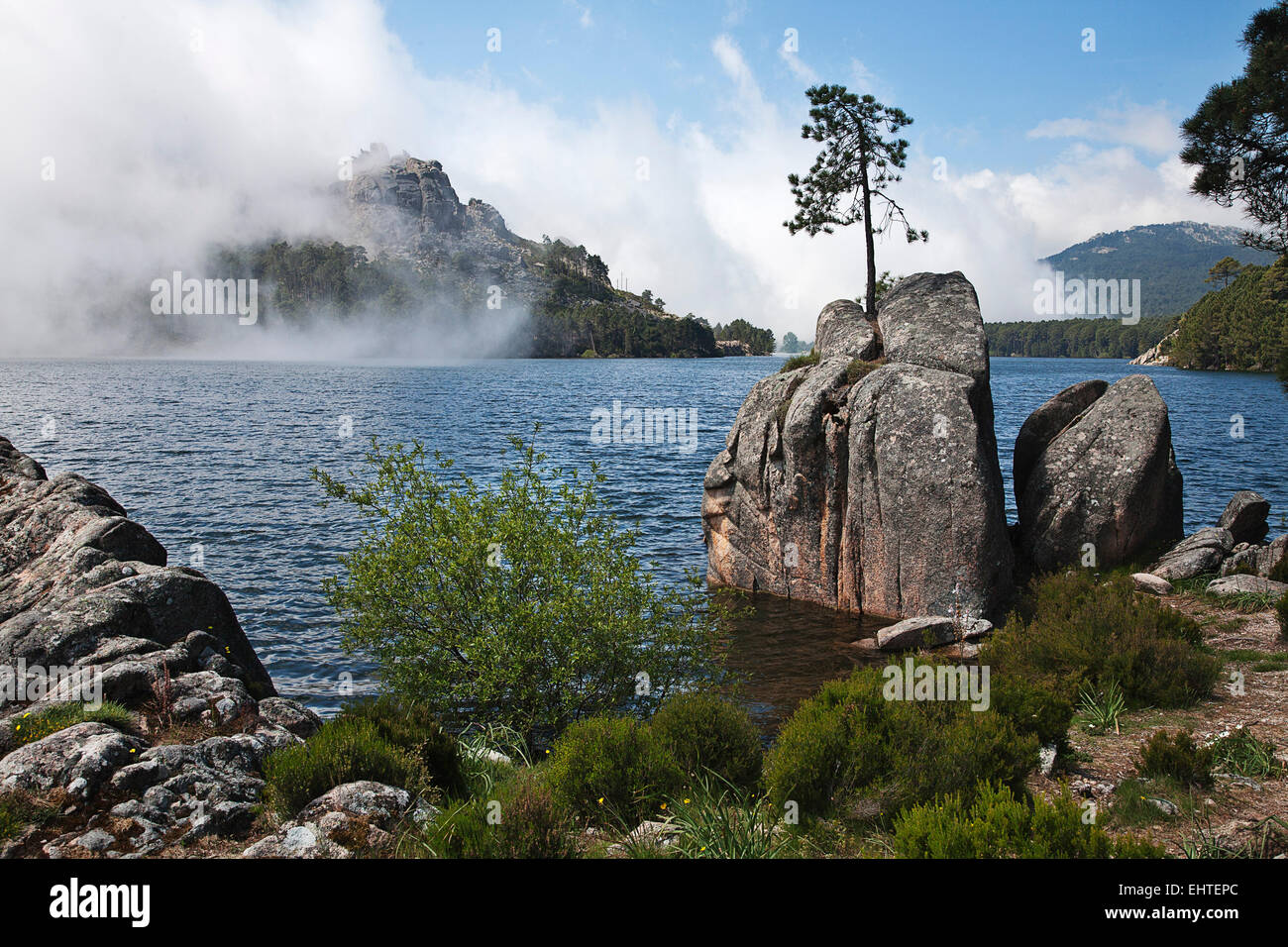 A lake in central Corsica near the mountain village of Zonza becomes a dramatic scene with incoming weather and clouds. Stock Photo