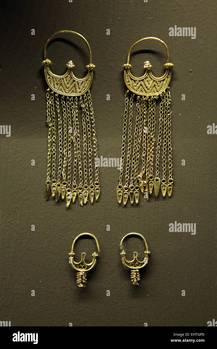 Great Moravian gold earrings, 9th century, Nove Mesto, Great Moravian Empire. Moravian Museum, Brno, Czech Republic. Exhibition 'Castles and Chateaux: Rediscovered and Celebrated' at the Prague Castle Riding School in Prague, Czech Republic. Pair of gold lunula earrings decorated with granulation and a pendant chain on the bottom hoop (above) and the pair of gold grape-cluster earrings with lunula woven of filigree wires (below). Stock Photo