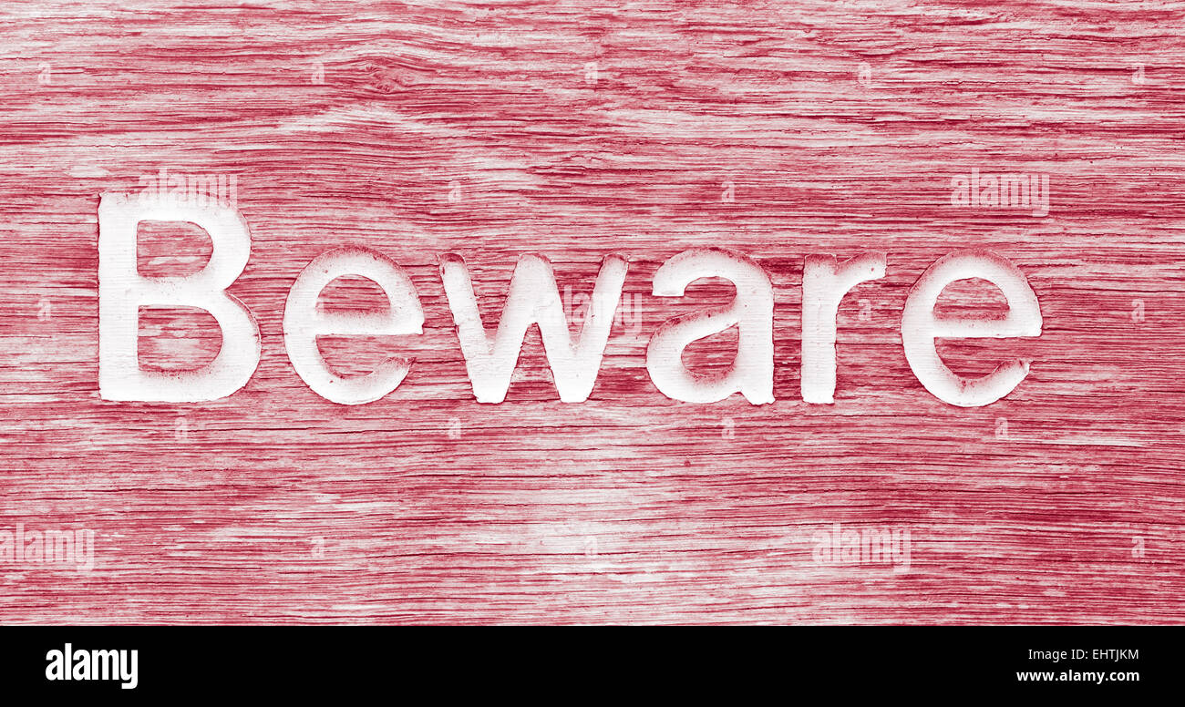 A wooden sign with beware written on it Stock Photo