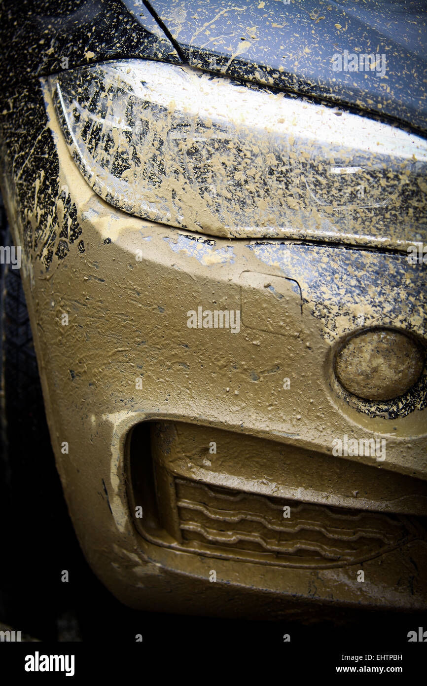 Color detail with the front side of an offroad car, covered in mud