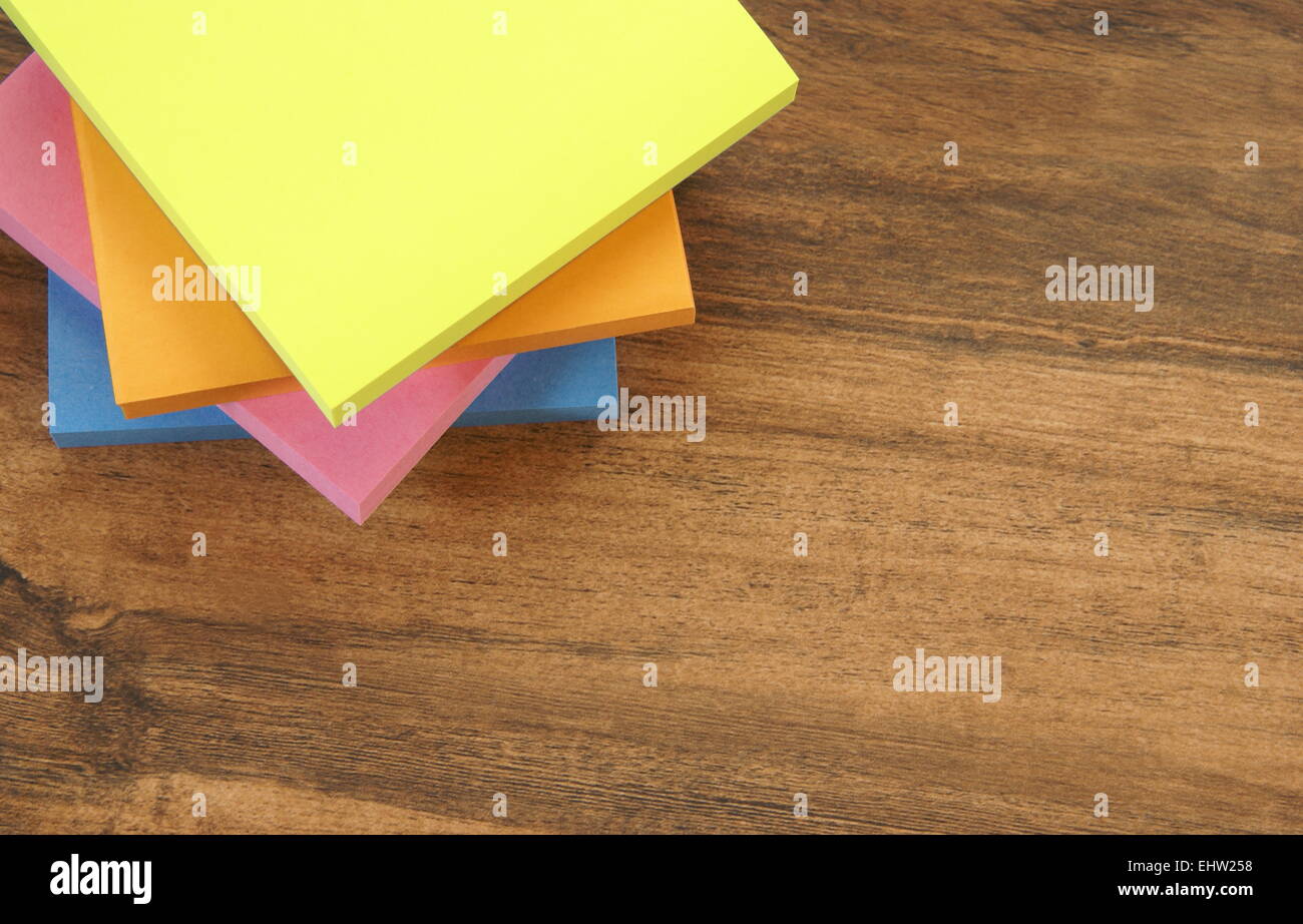 Multi colored notepads laying on a wooden plank board surface with copy