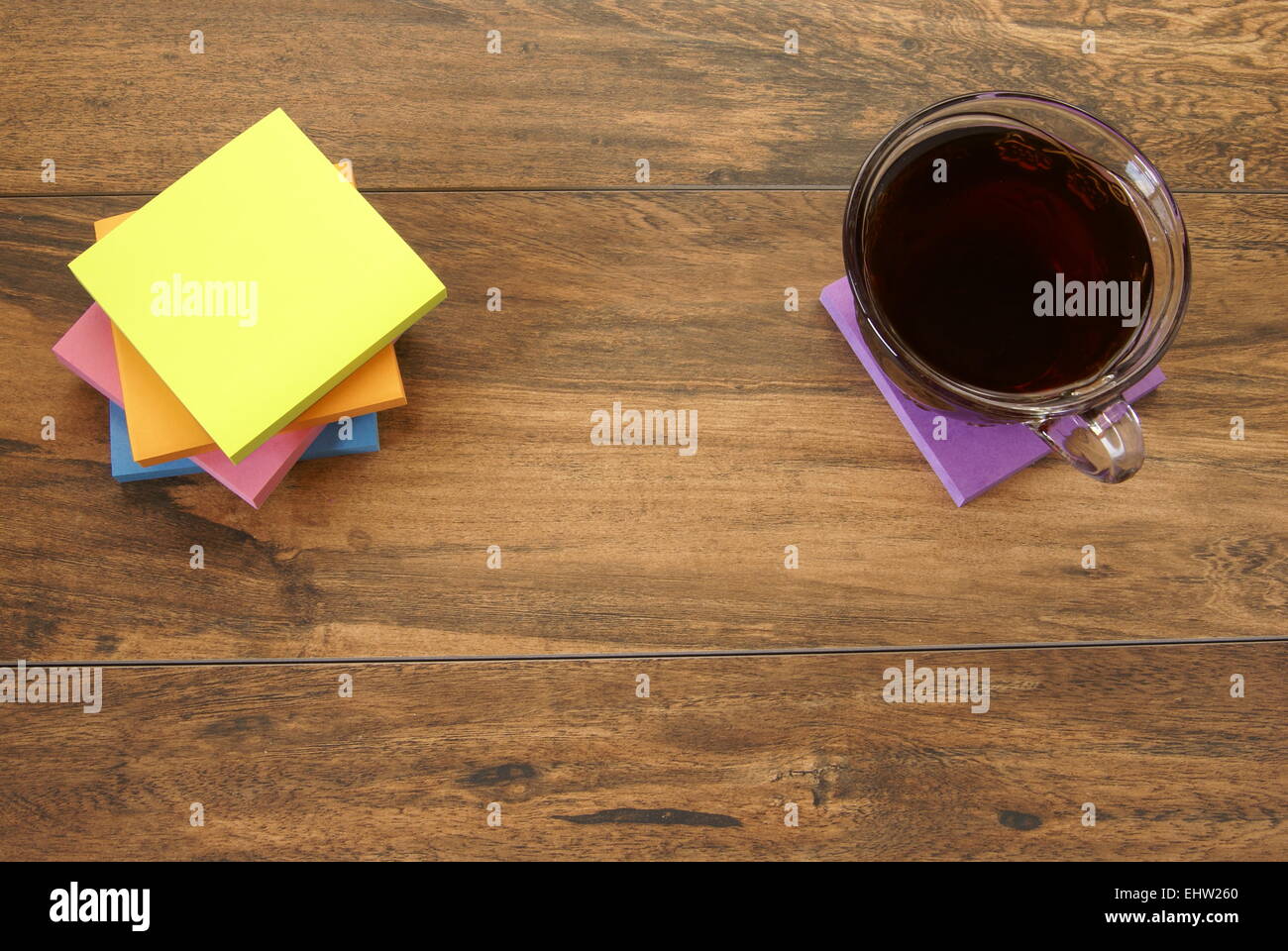 Multi colored notepads laying on a wooden plank board surface with copy