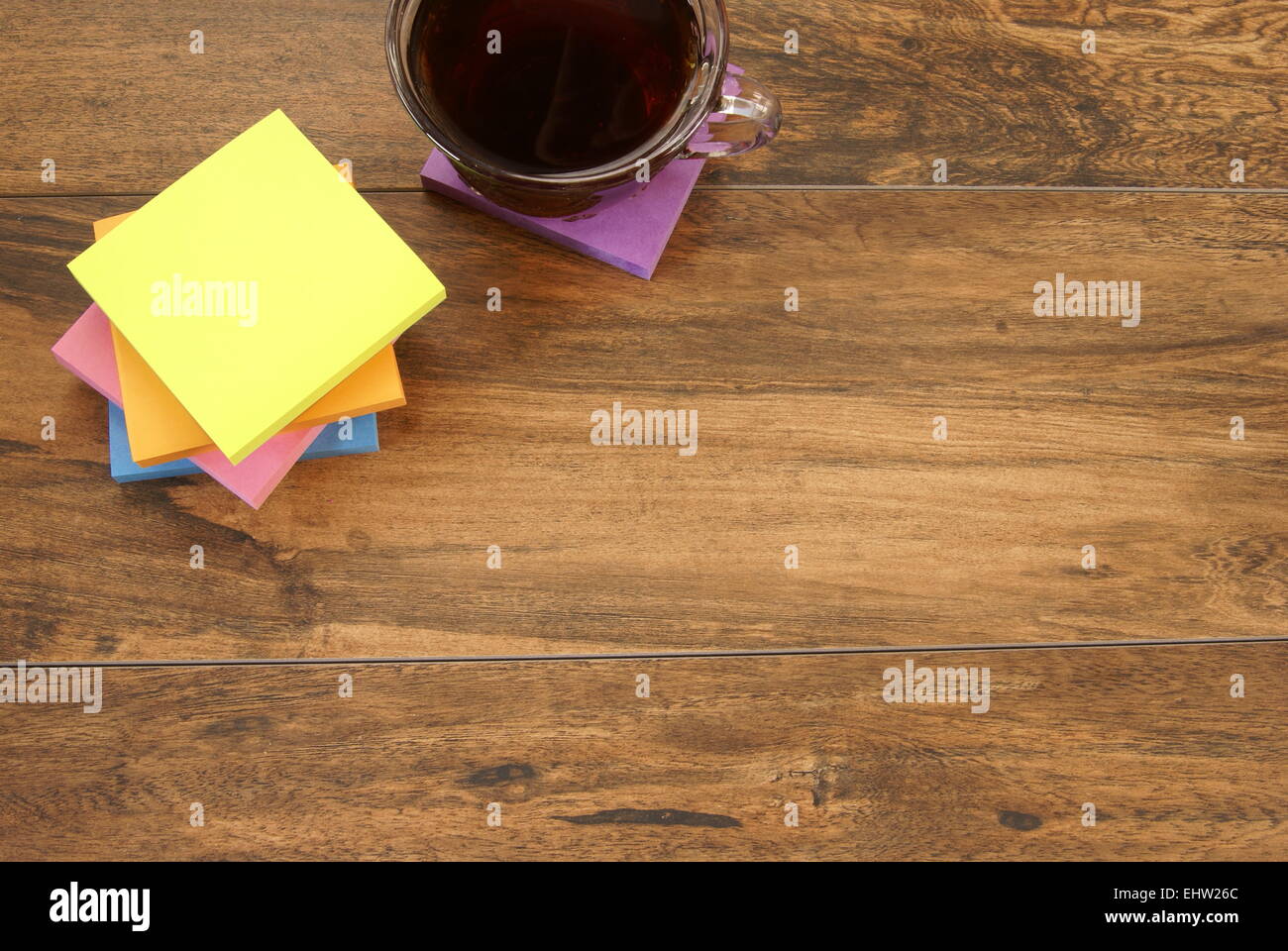Multi colored notepads laying on a wooden plank board surface with copy space Stock Photo