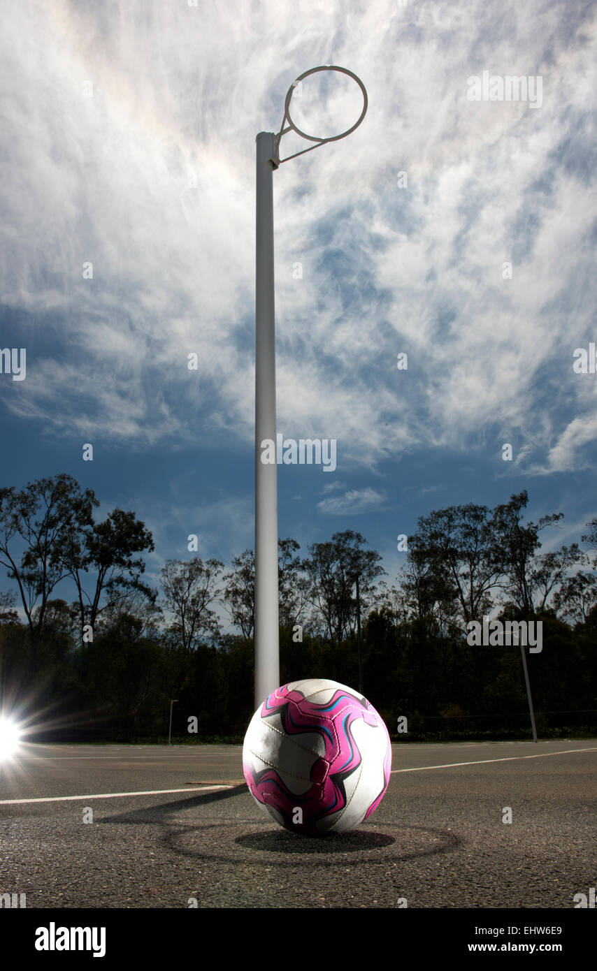 Netball resting on the ground, positioned in the shadow of the goal post. Stock Photo