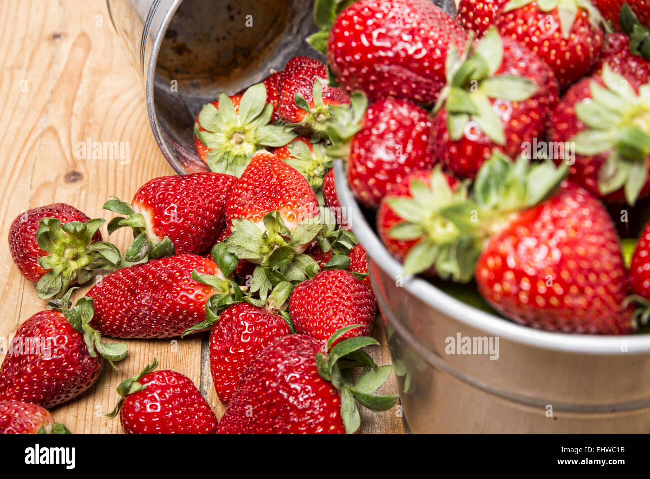 strawberries in a small metallic bucket placed on a old wooden table ...