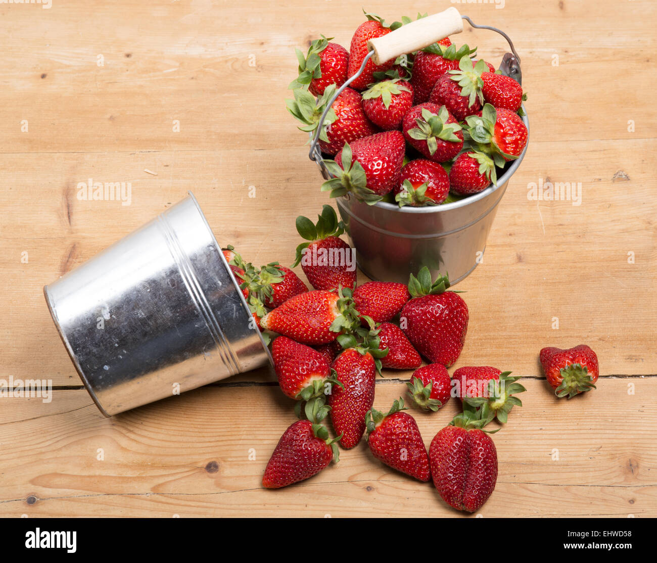 strawberries in a small metallic bucket placed on a old wooden table ...