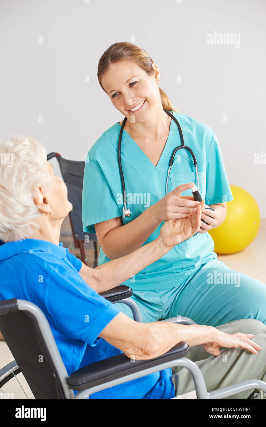 Blood glucose monitoring of old diabetes patient in a wheelchair Stock