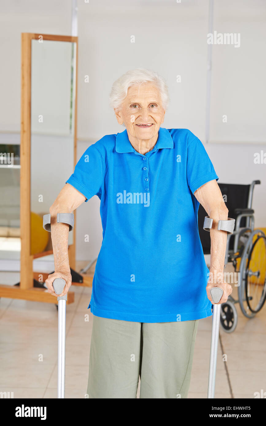Old woman with crutches smiling in physiotherapy room Stock Photo
