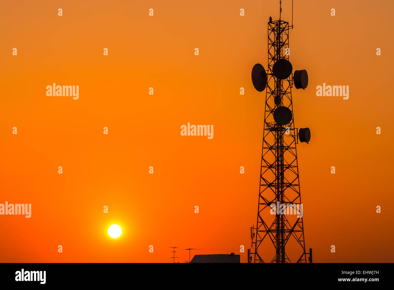 Telecommunication tower structure with sunset sky in silhouette background Stock Photo
