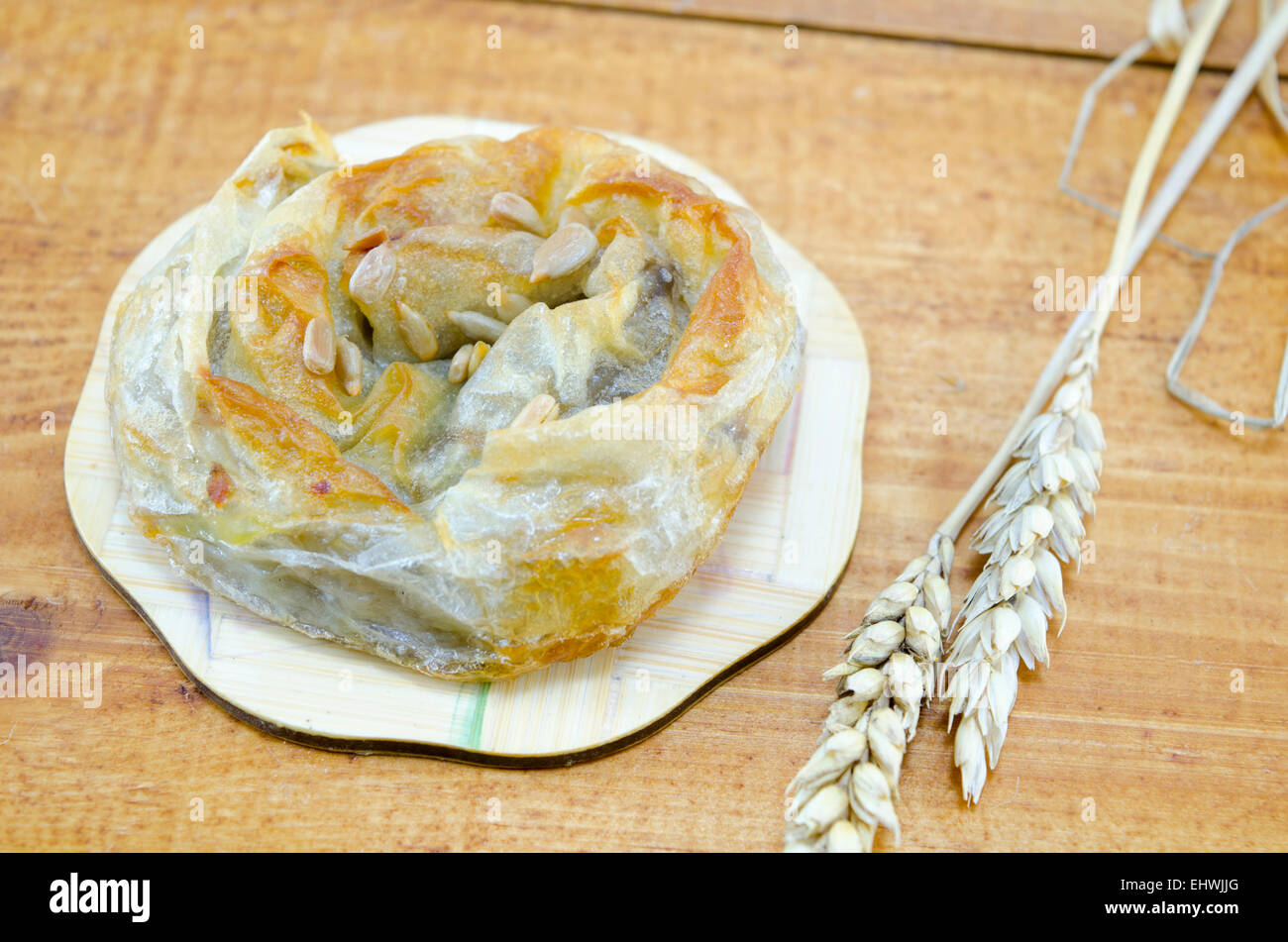 Savory meat pie with seeds on a wooden table decorated with wheat sticks Stock Photo