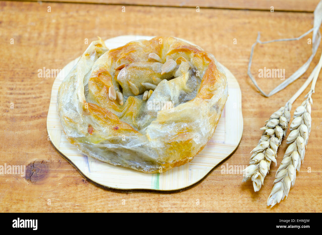 Savory meat pie with seeds on a wooden table decorated with wheat sticks Stock Photo
