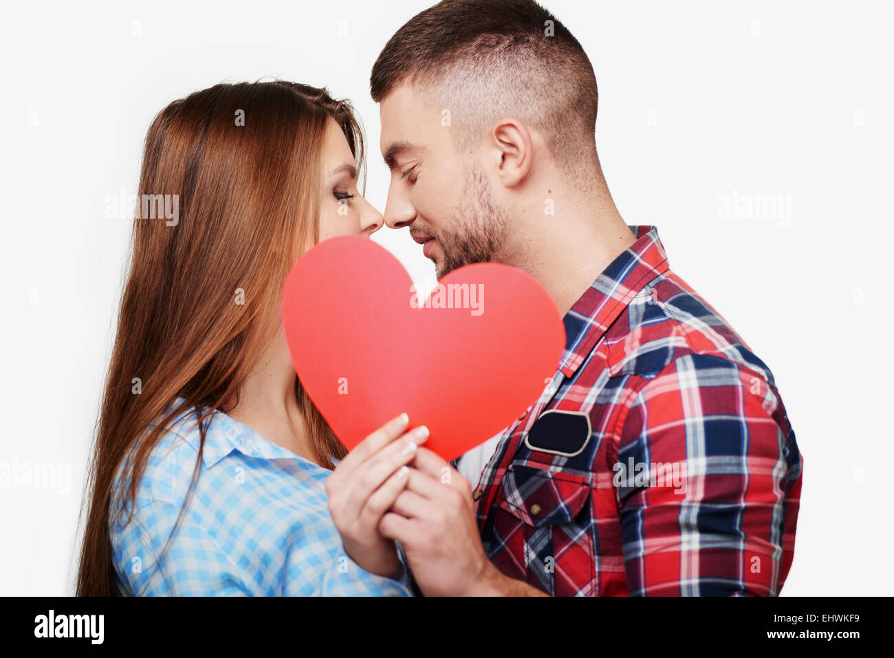Young couple is kissing behind red heart Stock Photo - Alamy