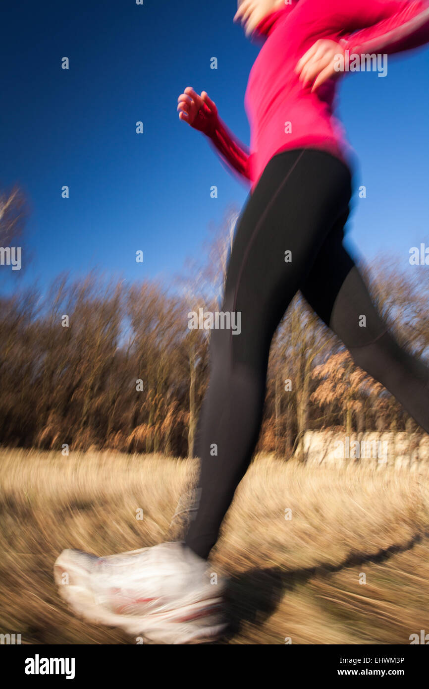 Young woman running outdoors on a lovely sunny winter/fall day (motion ...