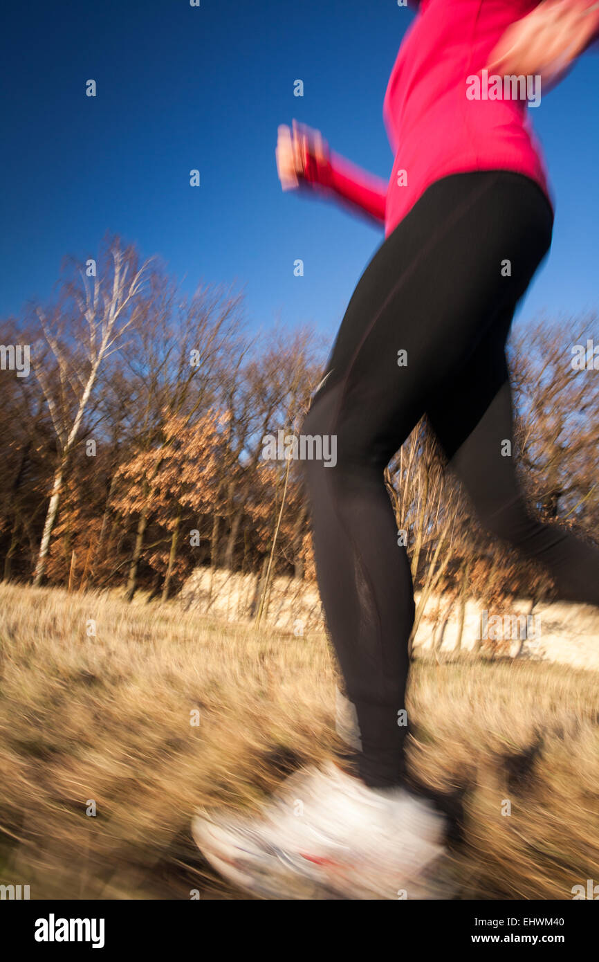 Young woman running outdoors on a lovely sunny winter/fall day (motion ...