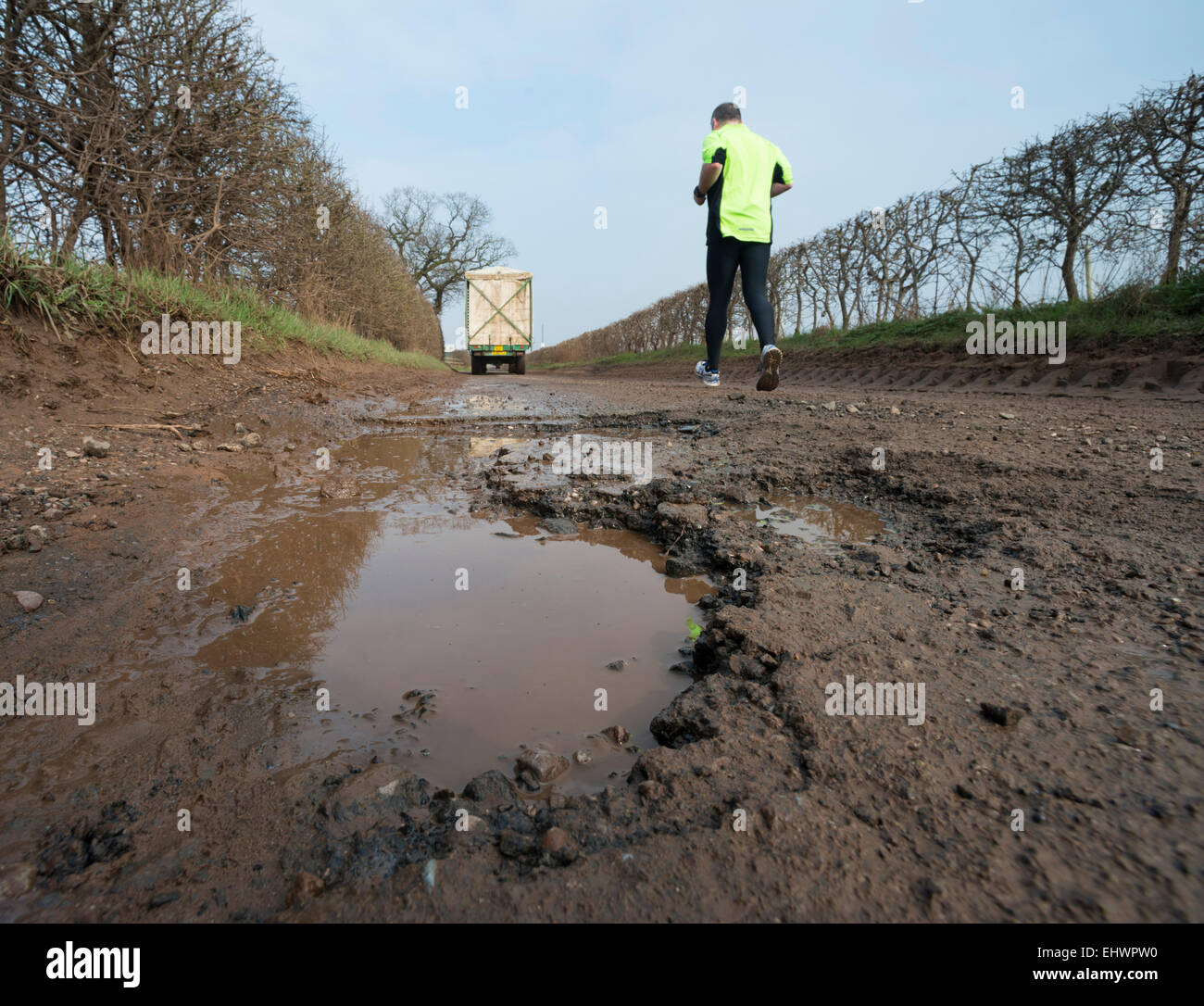 Pot holes in a country lane at Shifnal with jogger and lorry, Shropshire, England. Stock Photo
